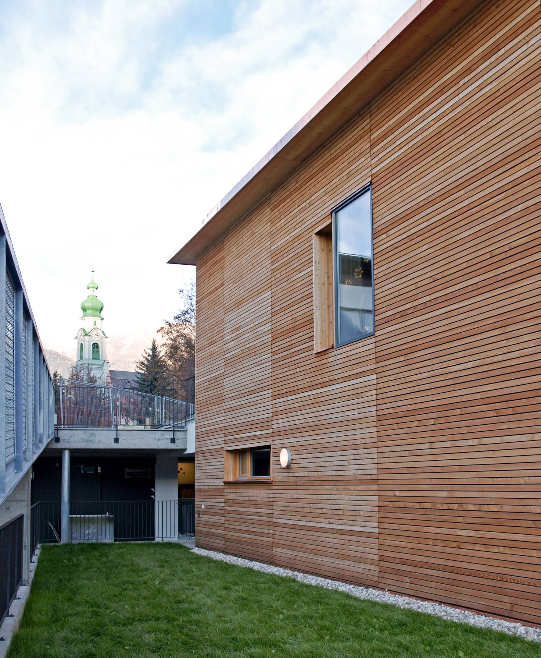 Neubau Kindergarten Toblach (2008–2009): Westseite mit Durchgang Richtung Dorf. Architekt Johannes Watschinger.